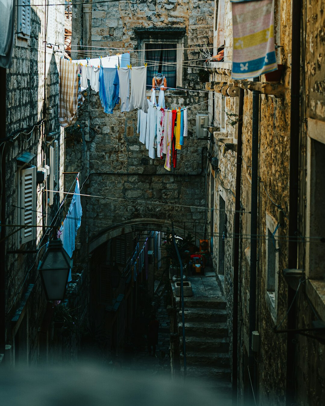 Narrow cobblestone alley with laundry hanging between buildings