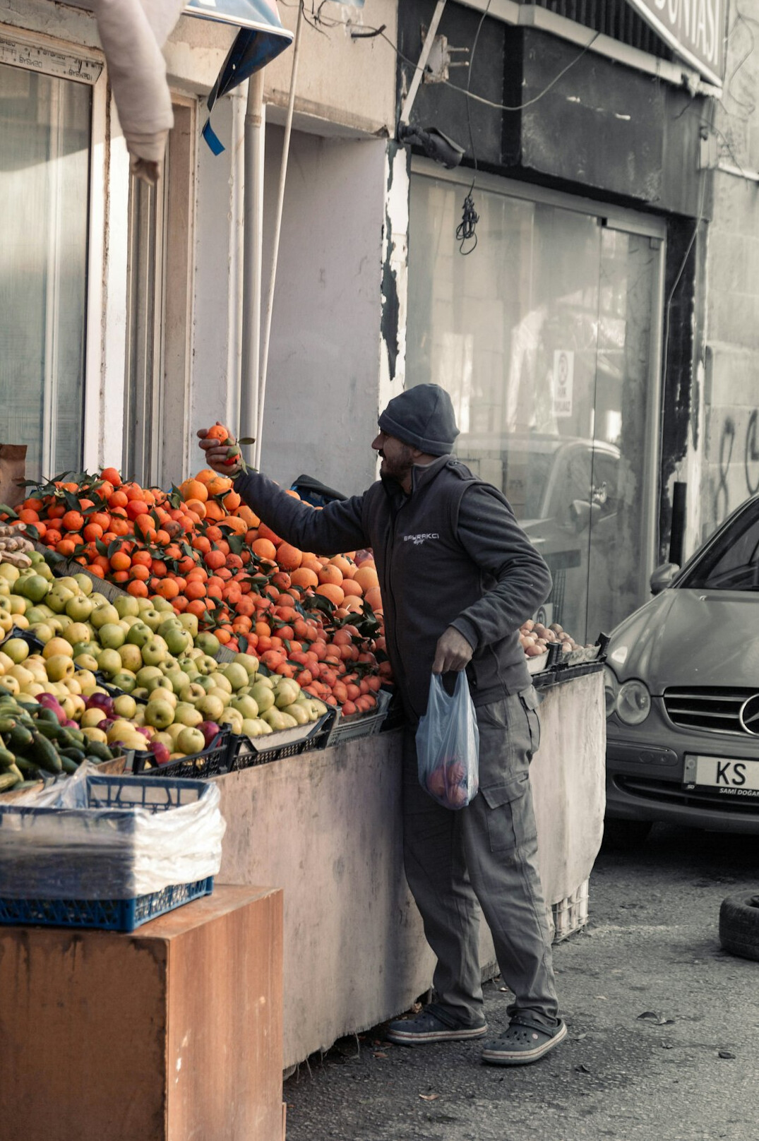 Street vendor arranging fruit at an outdoor market stall